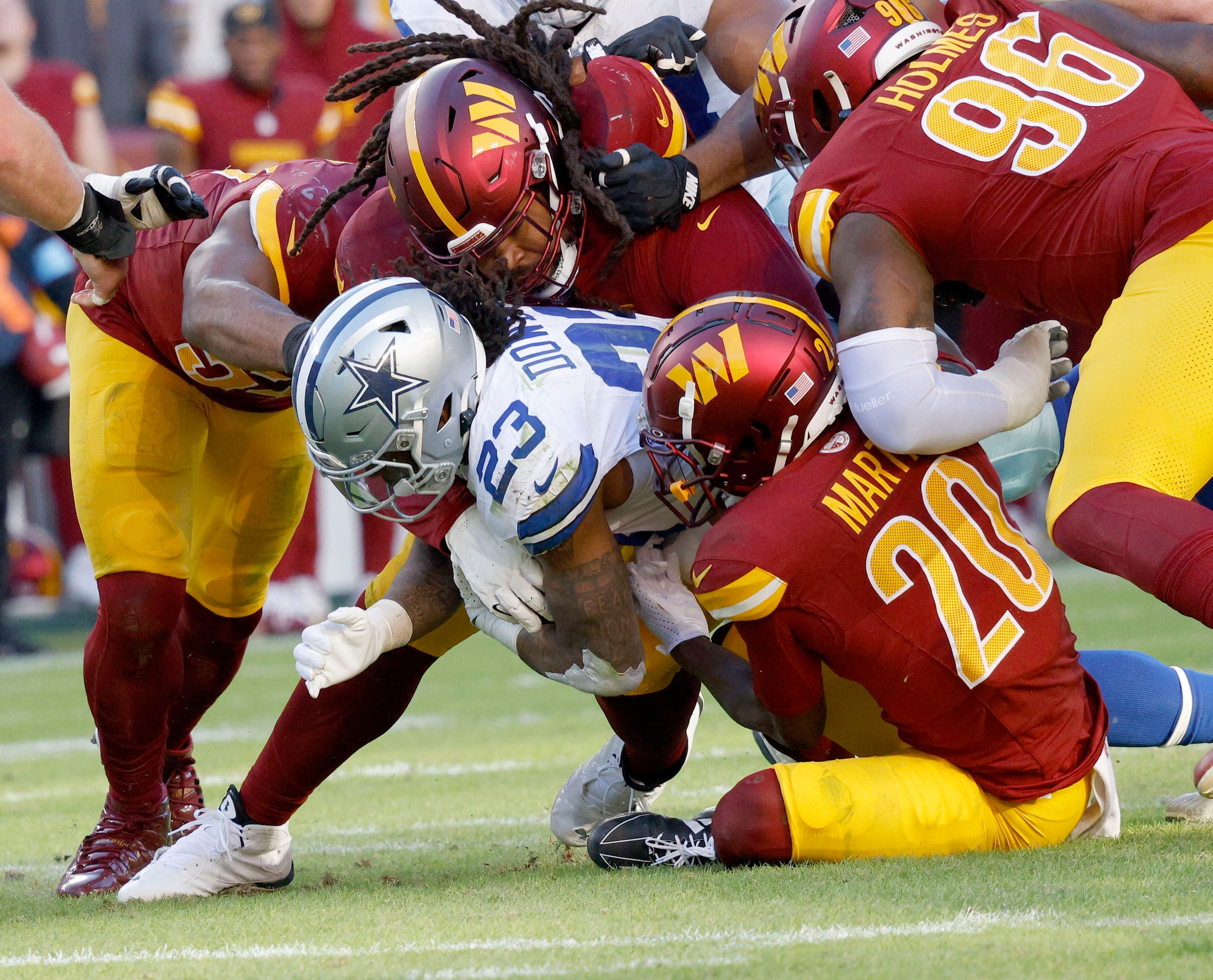 Dallas Cowboys running back Rico Dowdle (23) is tackled by Washington Commanders defense...