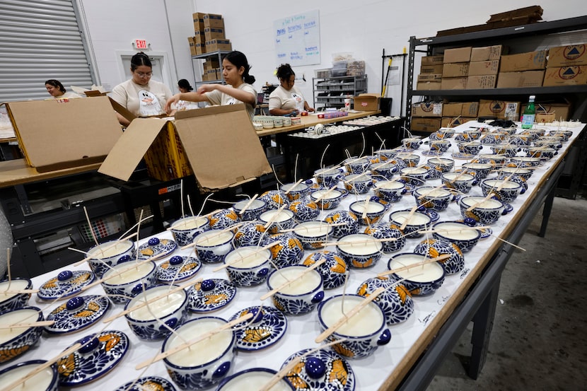 Team members make candles at “Luz Y Tierra, ” candle shop, which sells candles with...