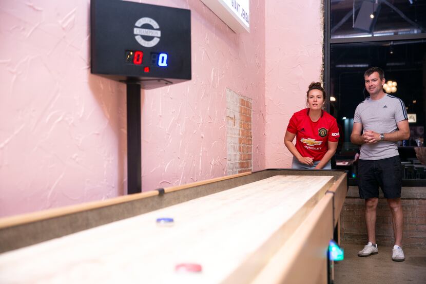 Pia Barnett, left, and Chris Hill, right, play shuffleboard at Punch Bowl Social. This photo...