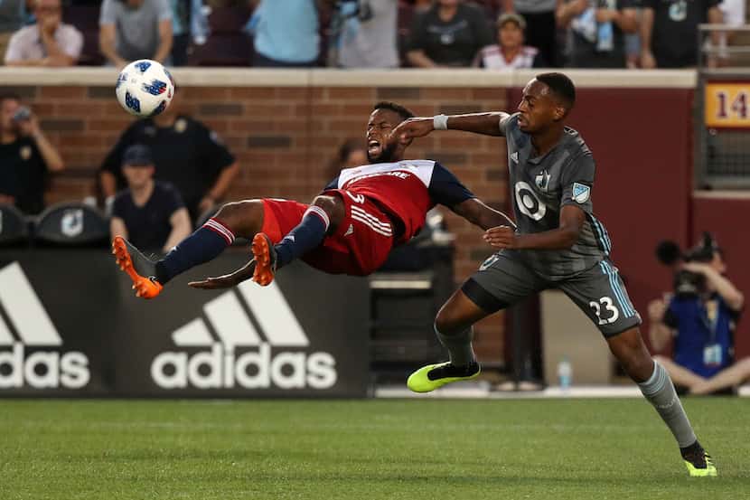 FC Dallas midfielder Kellyn Acosta (left) tries to clear the ball away from Minnesota United...