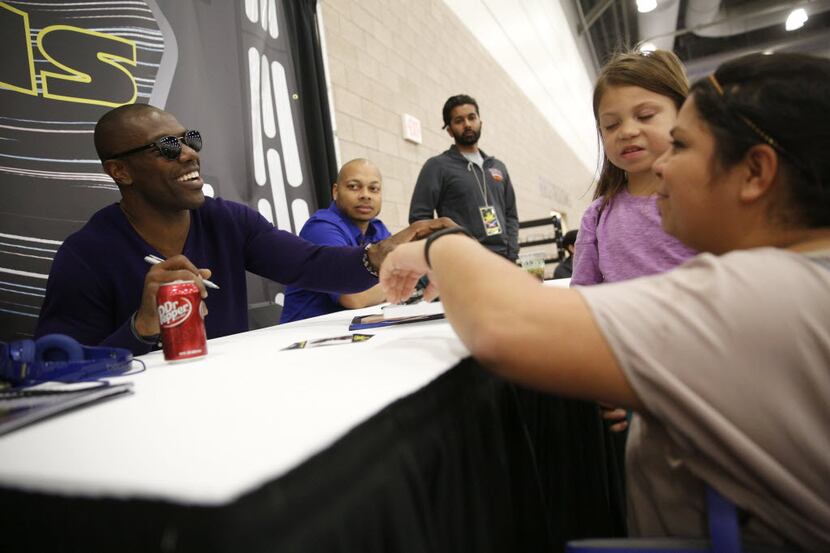 Former Dallas Cowboy Terrell Owens signs his autograph for Lisa Price and her daughter Ella...