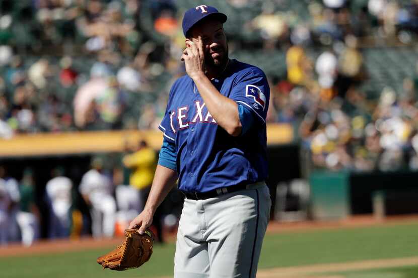 Texas Rangers starting pitcher Colby Lewis walks back to the dugout after being pulled from...