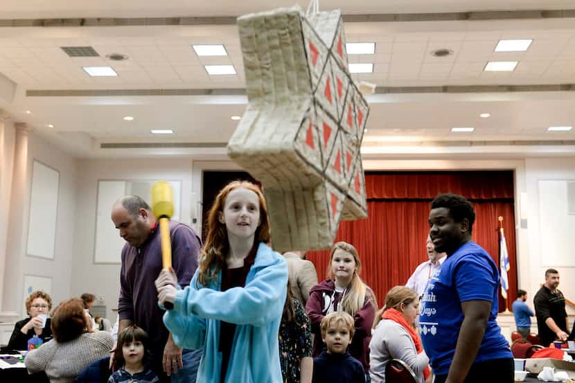 Children eagerly wait for candy to fall from a Star of David-shaped pinata during the Jewish...