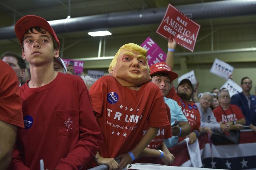 A young supporter wearing a Donald Trump mask watches as Republican presidential nominee...