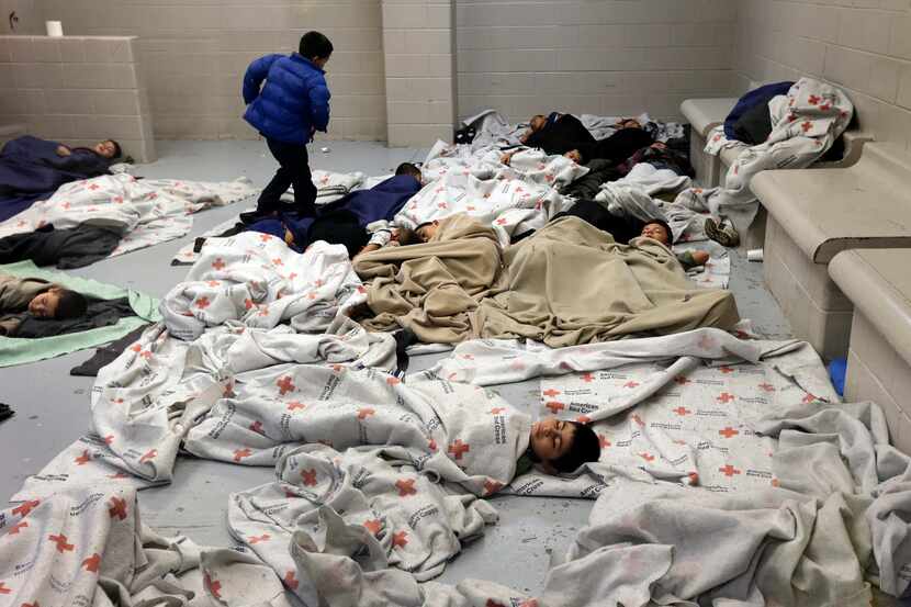 FILE - In this June 18, 2014, file photo, detainees sleep in a holding cell at a U.S....