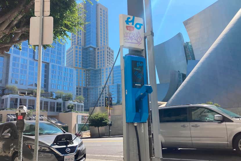 An electric vehicle charges on a pole-mounted charger in Los Angeles on Oct. 4, 2022. EV...