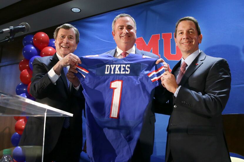 New SMU head football coach Sonny Dykes, center, holds up a jersey with university president...