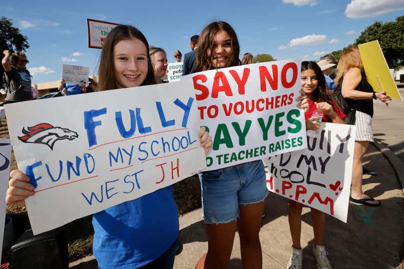 Shadia Jaber, 14, left, and Maya Howery, 13, both from West Junior High School, hold signs...