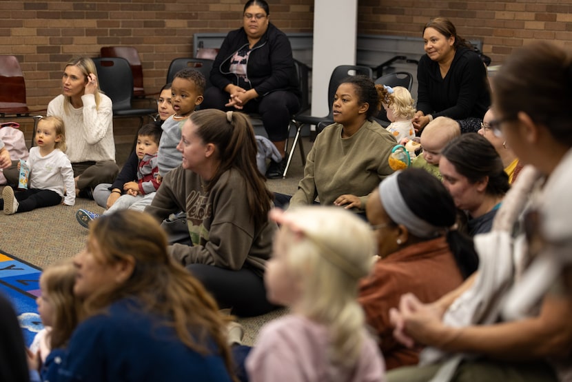 Parents and caretakers watch as Susan McGinnis reads to children during their weekly story...