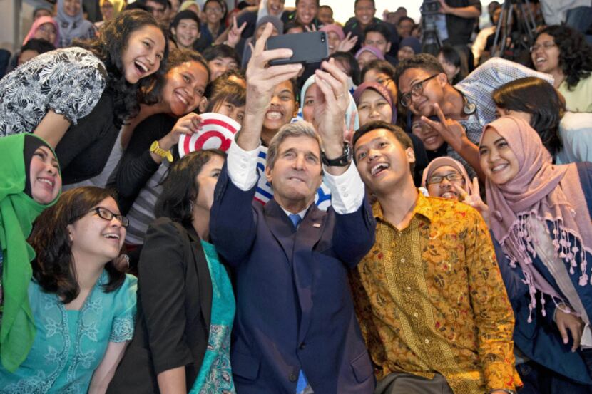 U.S. Secretary of State John Kerry takes a photo with a group of students before delivering...
