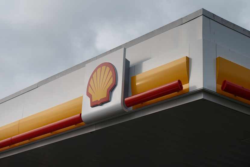 The company logo sits above the forecourt of a gas station operated by Royal Dutch Shell Plc...