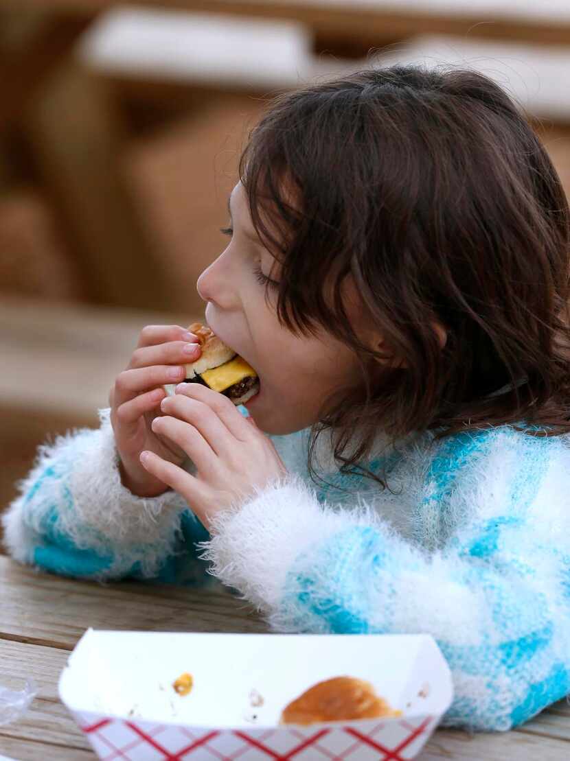 Kailey Reyes, 7, eats a burger at Richardson Food Truck Park on Saturday.