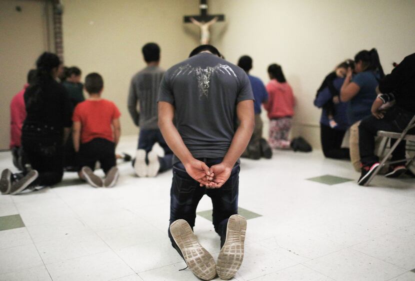 Migrants pray at an Annunciation House shelter for migrants on October 13, 2018 in El Paso....