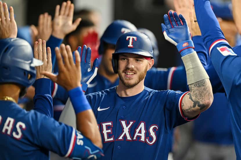 Texas Rangers' Jonah Heim (28) celebrates in the dugout with teammates after his three-run...