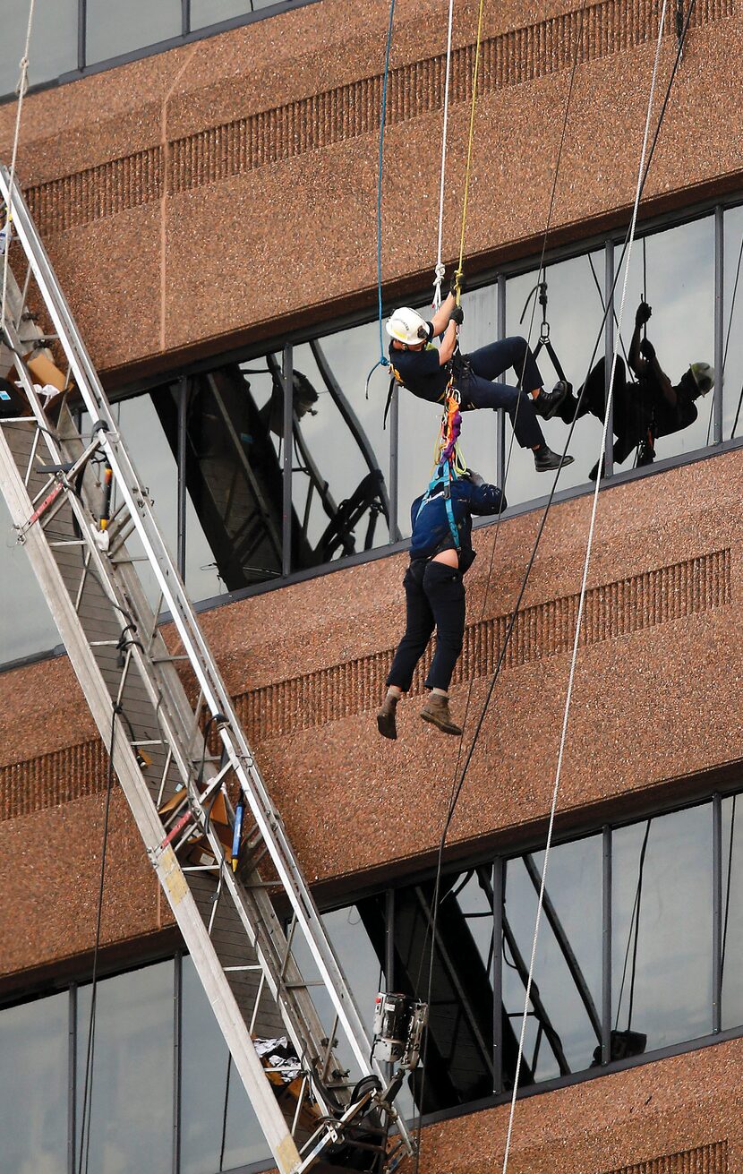 Dallas Fire Department Urban Search and Rescue member Jonathan Formby (top) lowers one of...