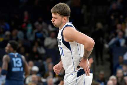 Dallas Mavericks guard Luka Doncic holds his side after falling in the first half of an NBA...