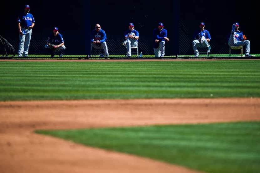 Texas Rangers watch the second inning of a spring training game against the Seattle Mariners...