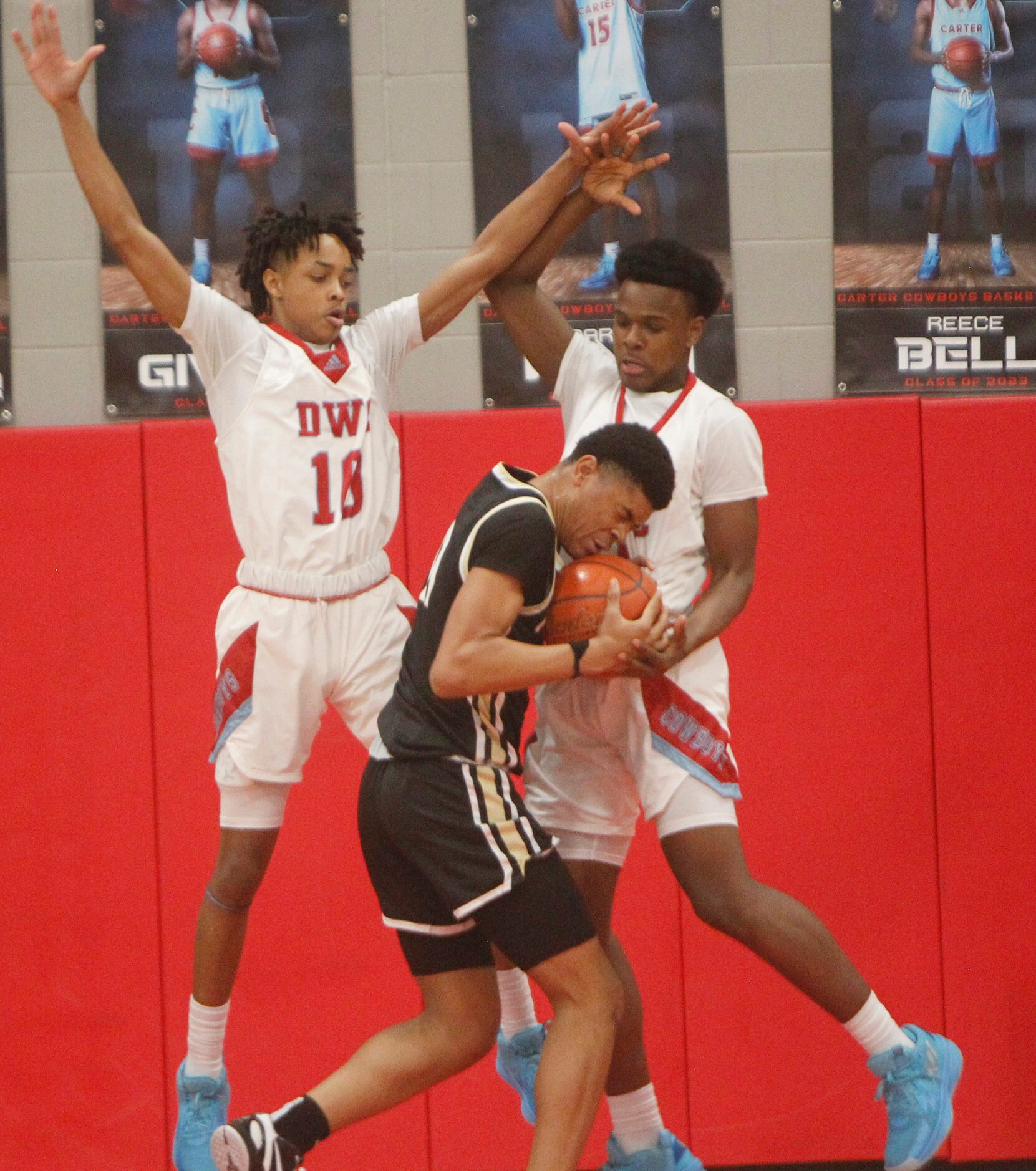 Dallas Pinkston's Bryce Dixon (11)center, winces as he encounters the tight defense of...