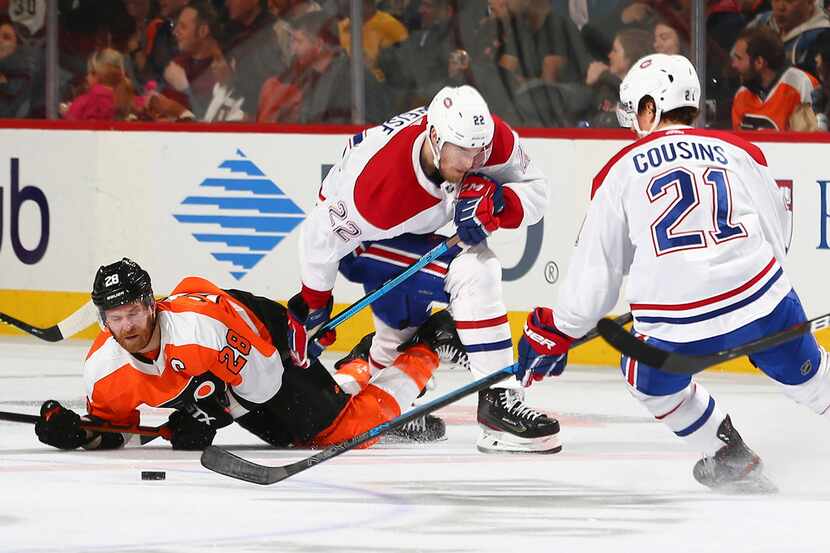 Claude Giroux of the Philadelphia Flyers falls to the ice in front of Dale Weise (22) and...