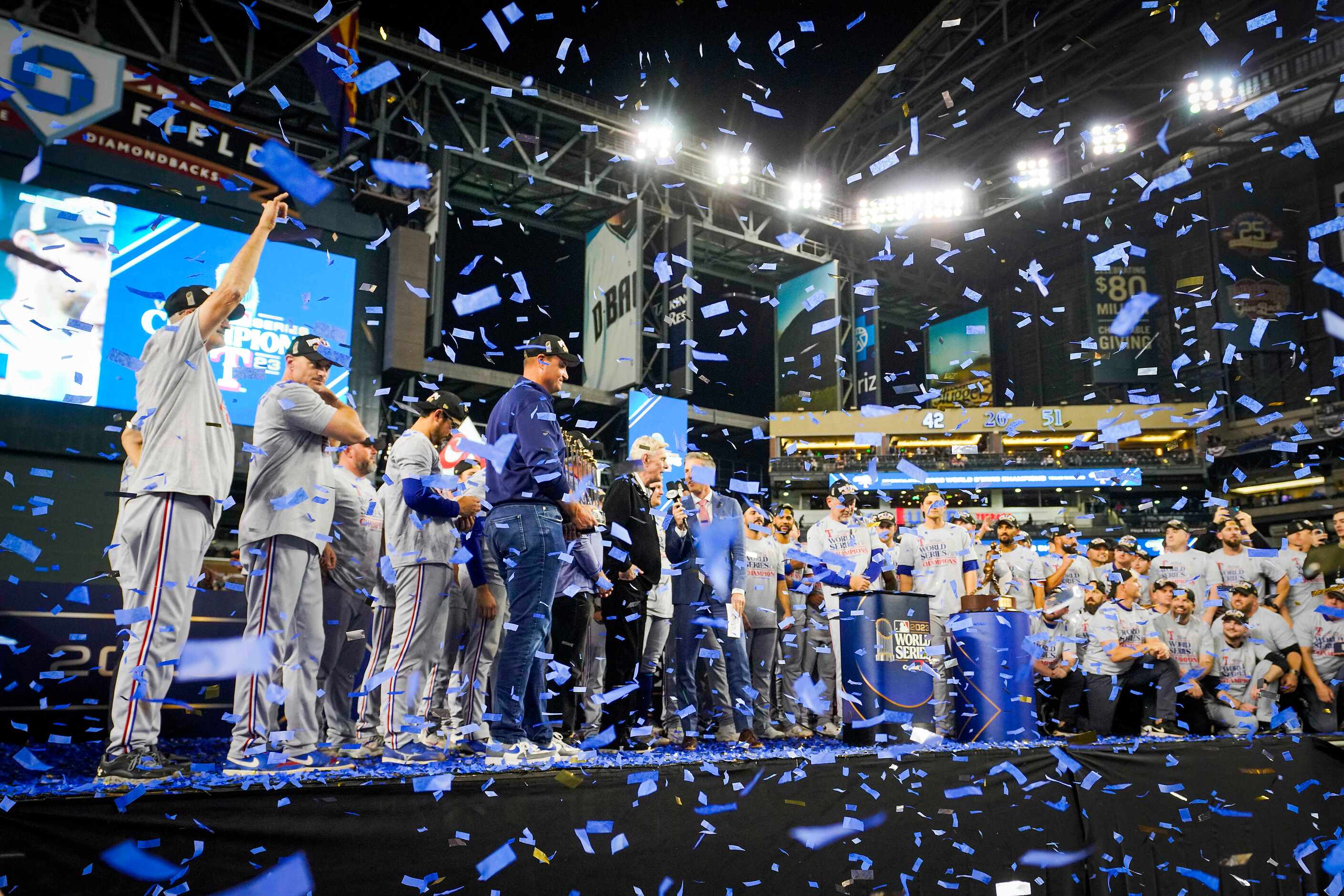 Texas Rangers general manager Chris Young holds the Commissioner’s Trophy as confetti falls...