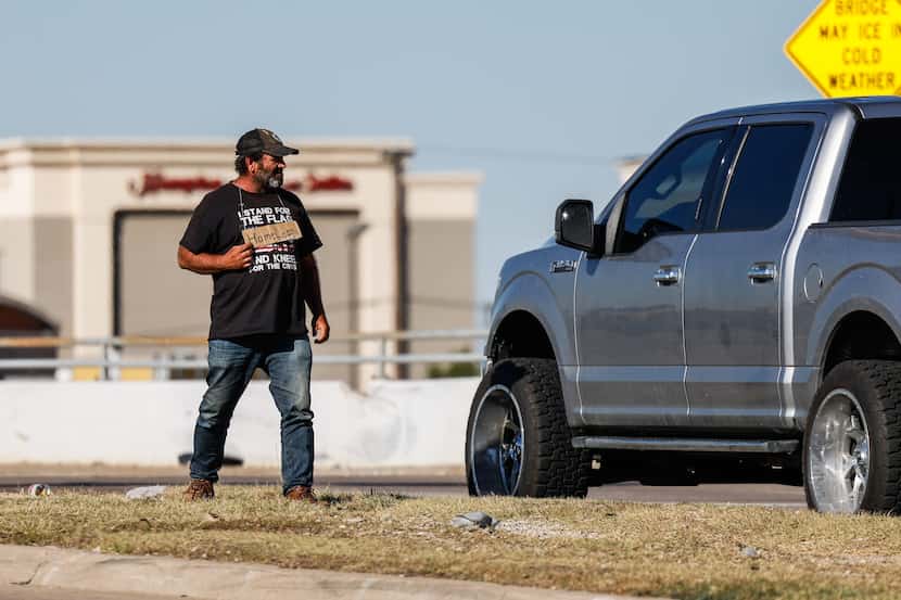 A man stands on a median in Dallas soliciting money from a driver in October 2022.