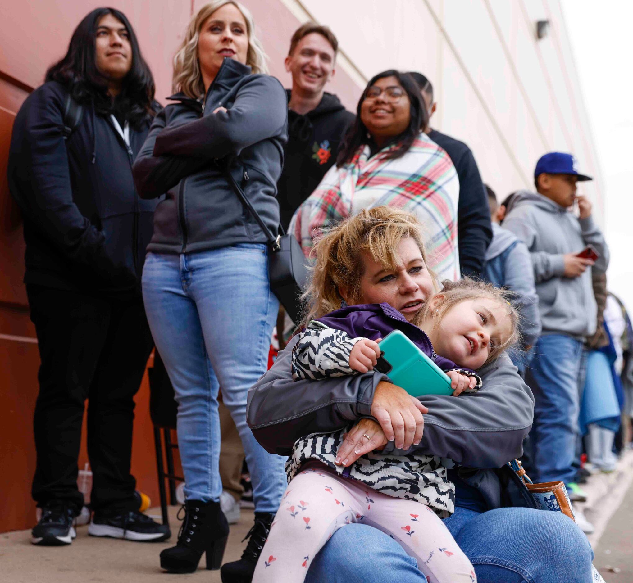 Fallon Marse of Dallas holds her daughter Gracen Rogers, 2, as they wait in line alongside...