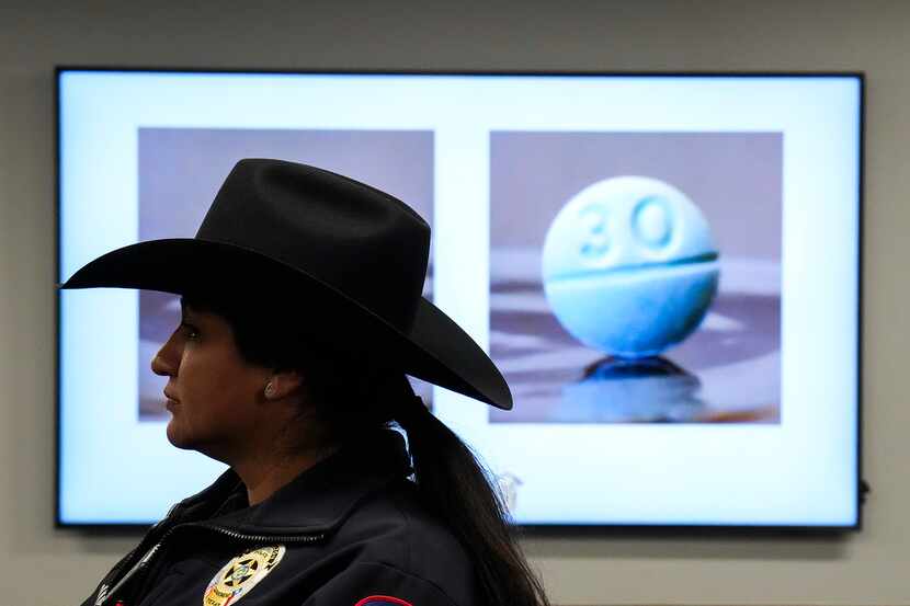 An M30 pill is seen on a monitor behind Carrollton police spokeswoman Isamar Leguizamo...