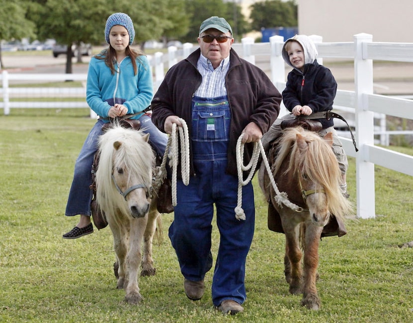 Hannah Greer (left), 10, of Allen, and Wade Bishop (right), 3, of Plano, are led by Tony...