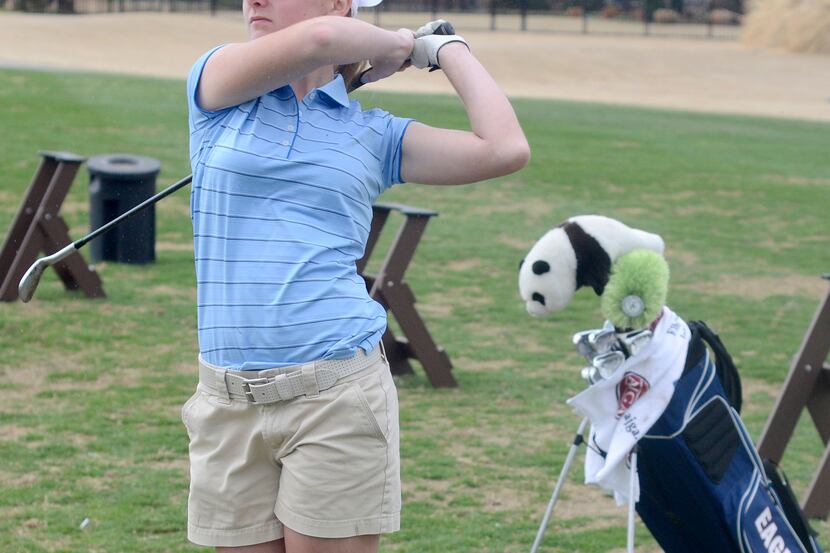 Golfer Maddie Szeryk follows through with her swing while practicing at the driving range,...