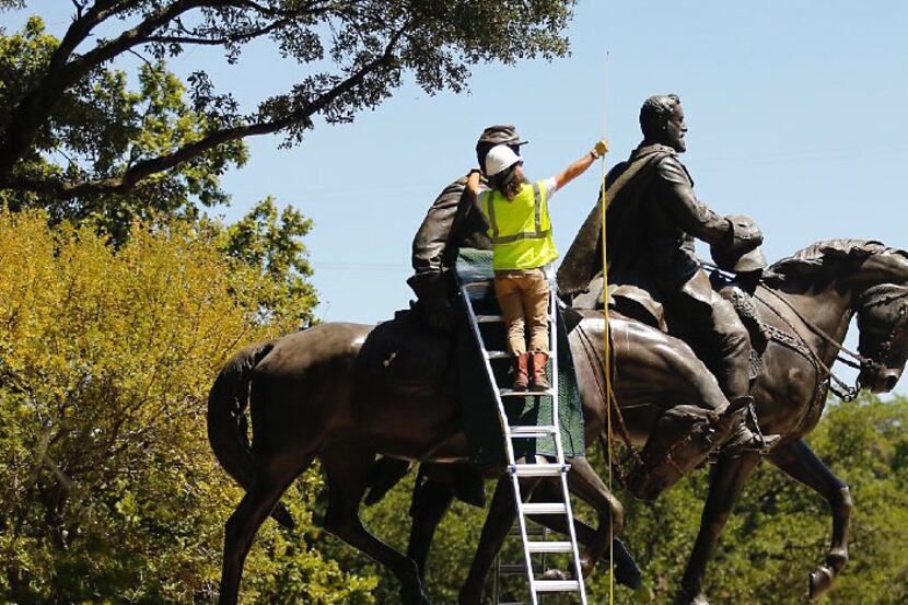 A crewman measure the height of the Robert E. Lee statue as they prepare to remove it from...
