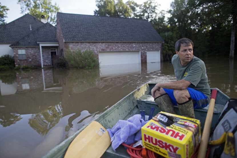 David Key boats away from his flooded home after reviewing the damage in Prairieville, La.,...