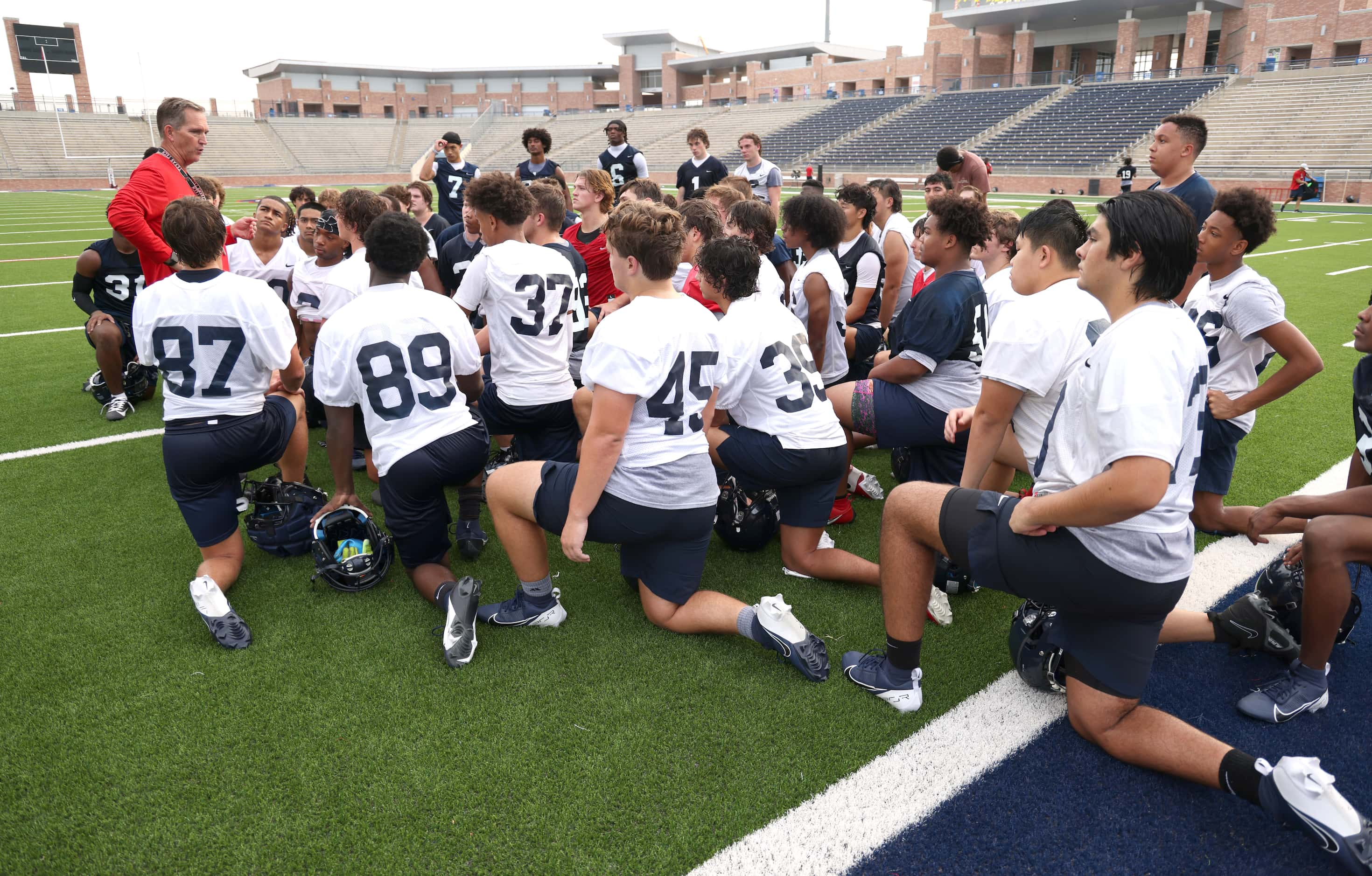 Allen head football coach Lee Wiginton, left, shares feedback with Eagles players at the...