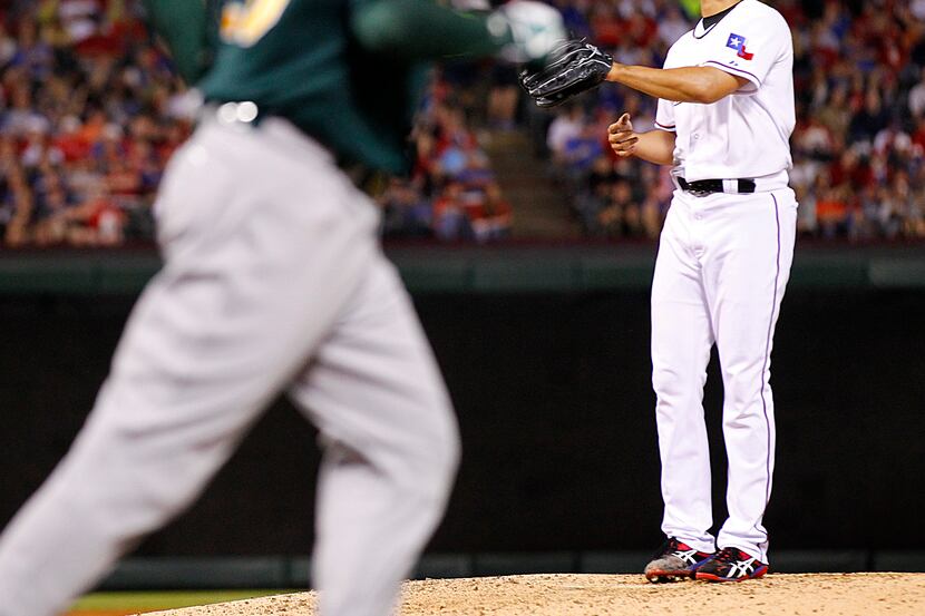 Texas Rangers starting pitcher Yu Darvish (11) walked Oakland Athletics third baseman Josh...