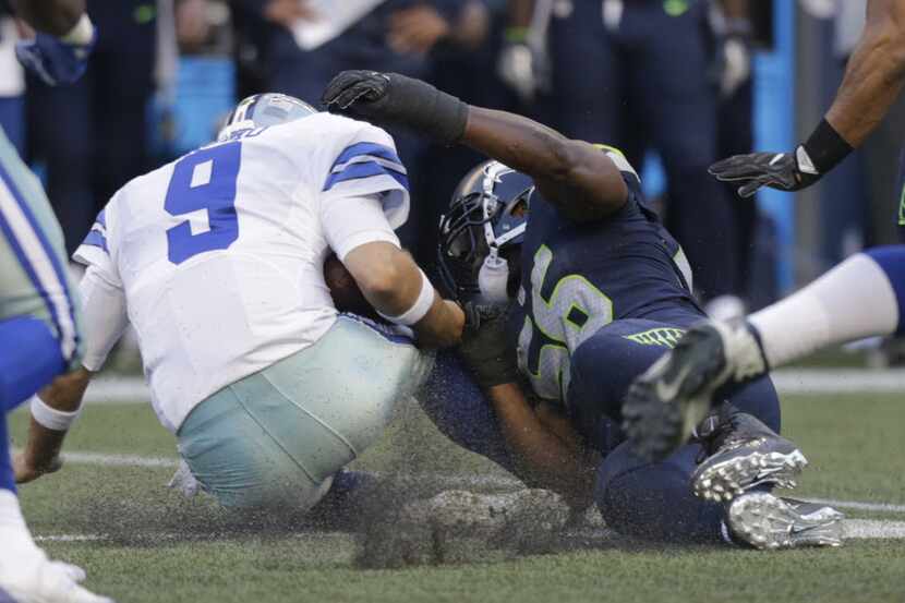 Dallas Cowboys quarterback Tony Romo (9) is tackled by Seattle Seahawks defensive end Cliff...