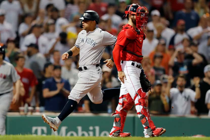 New York Yankees' Rougned Odor, left, scores behind Boston Red Sox's Connor Wong on a single...