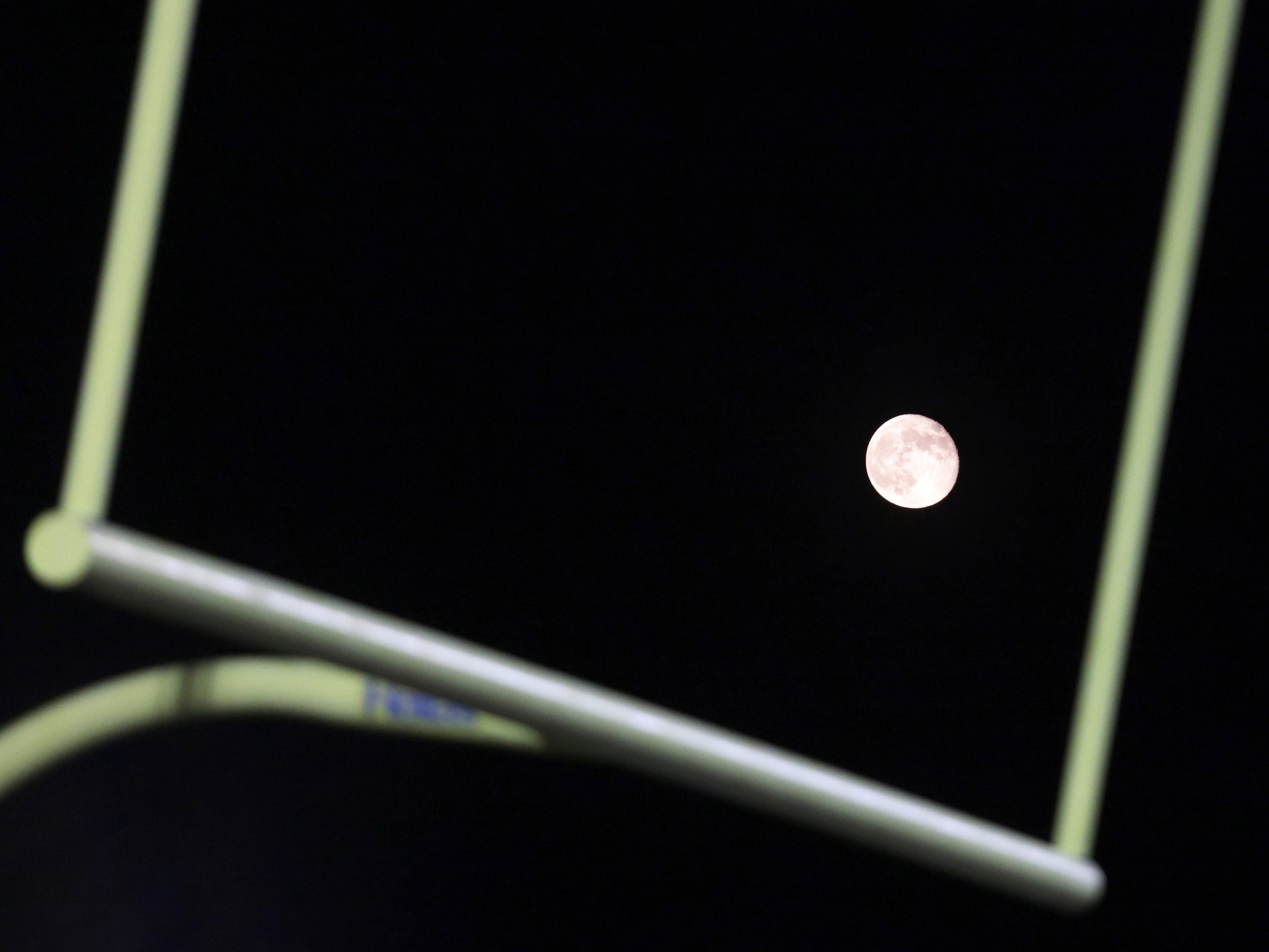 The moon peeks out from behind the goalpost during the Prosper Walnut Grove High School...