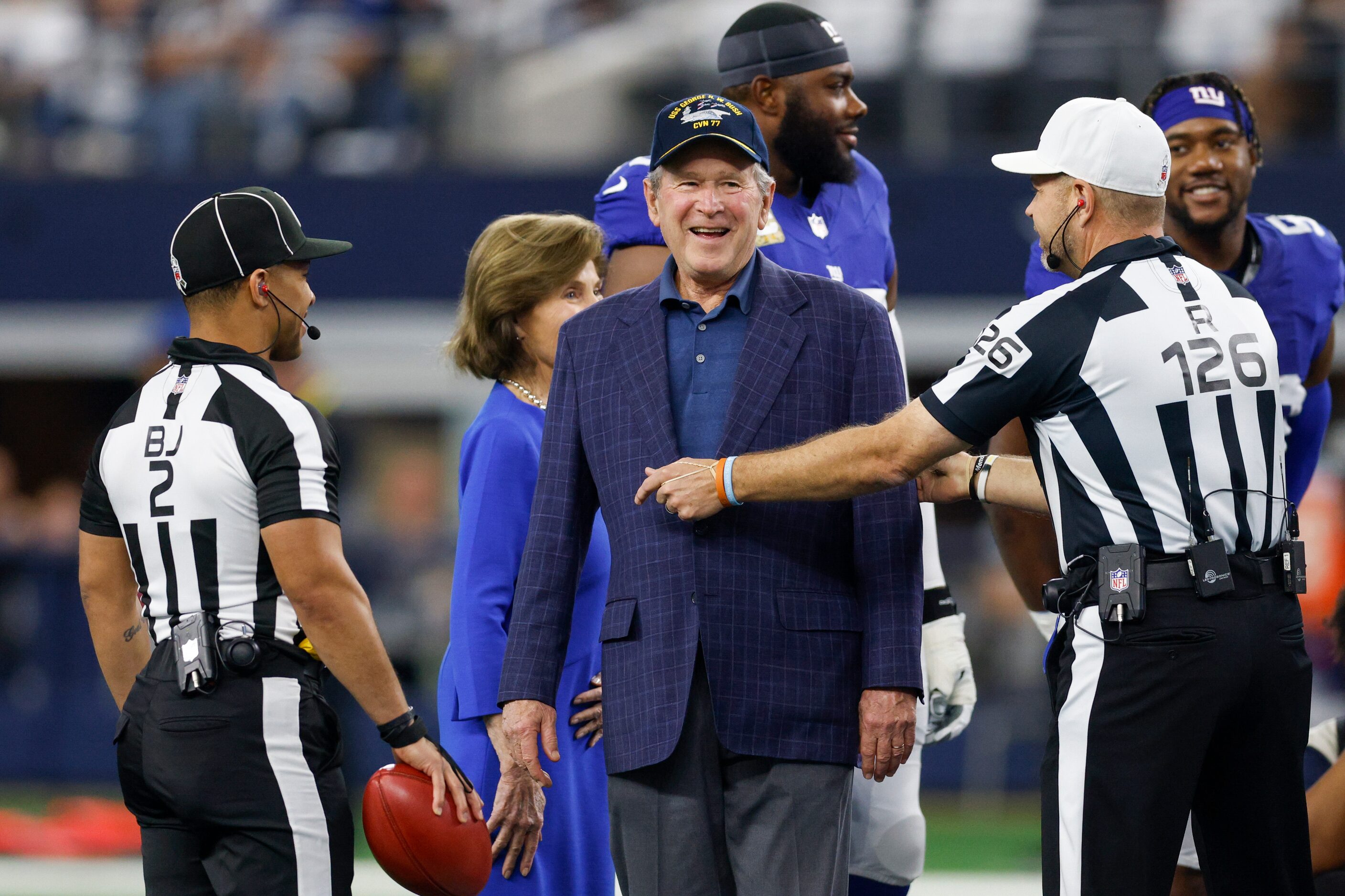 Former President George W. Bush laughs before performing the coin toss before an NFL game...