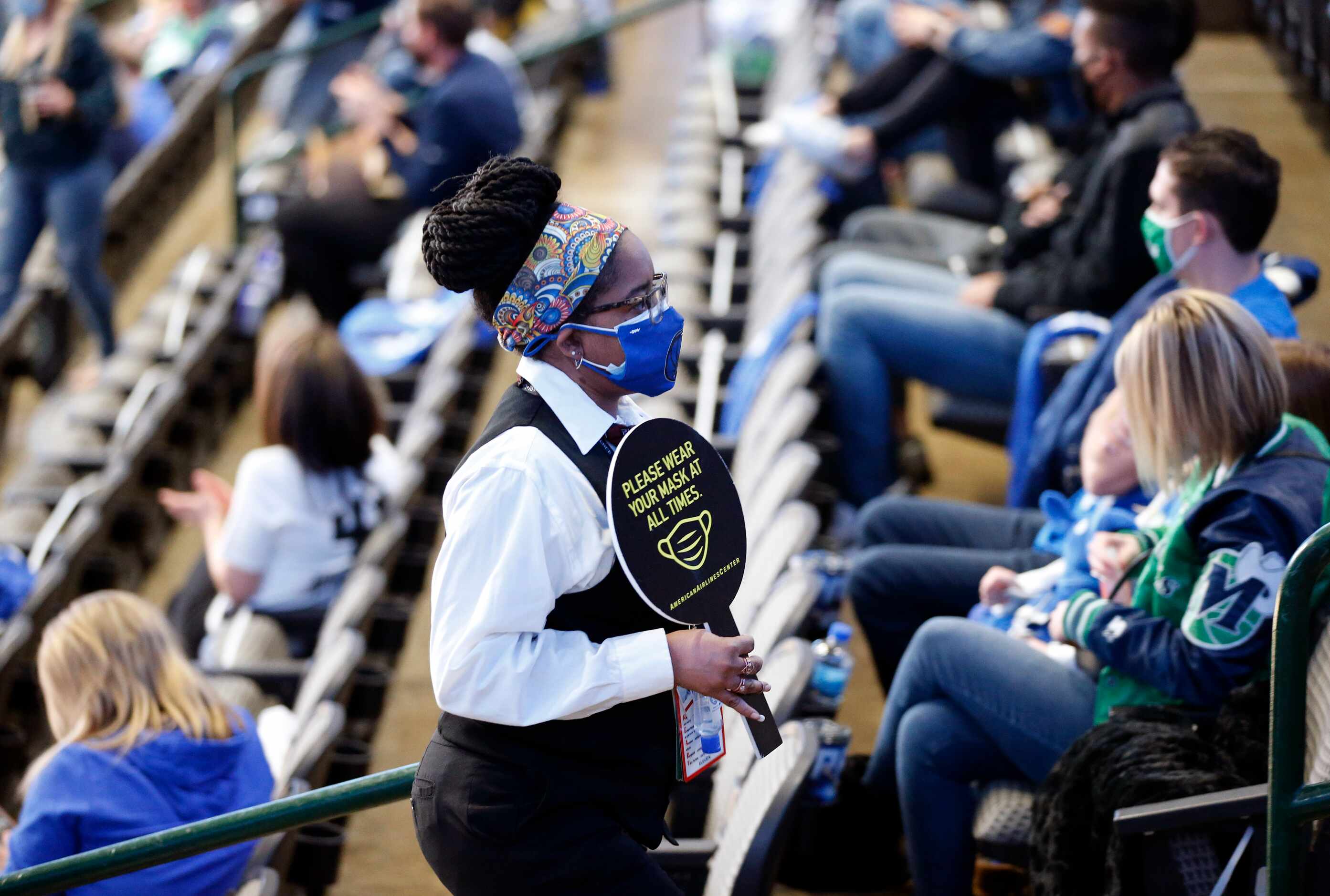 An American Airlines Center usher reminds Dallas Mavericks fans to wear their mask during...