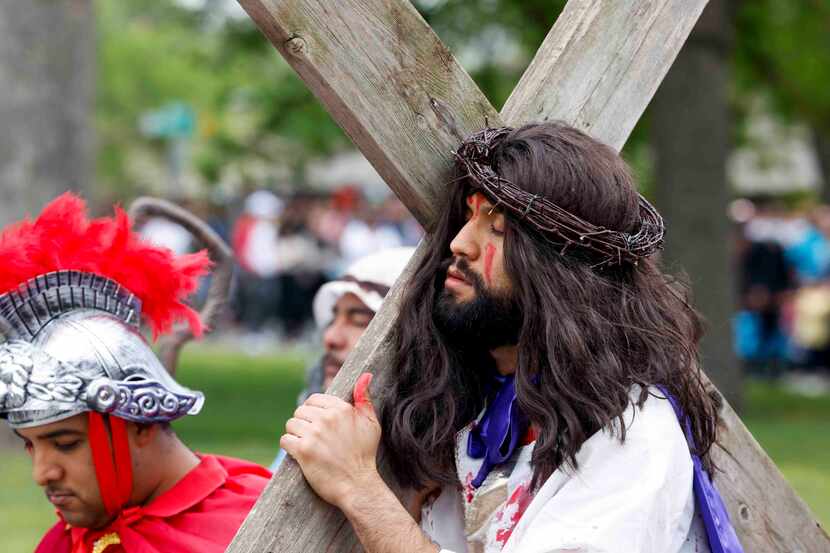 On Good Friday, Jesse Mendoza dressed as Jesus Christ closes his eyes ash carries a cross...