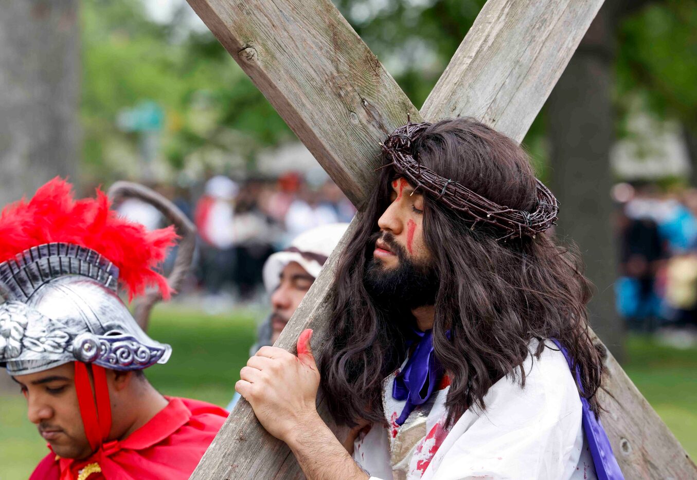 On Good Friday, Jesse Mendoza dressed as Jesus Christ closes his eyes ash carries a cross...