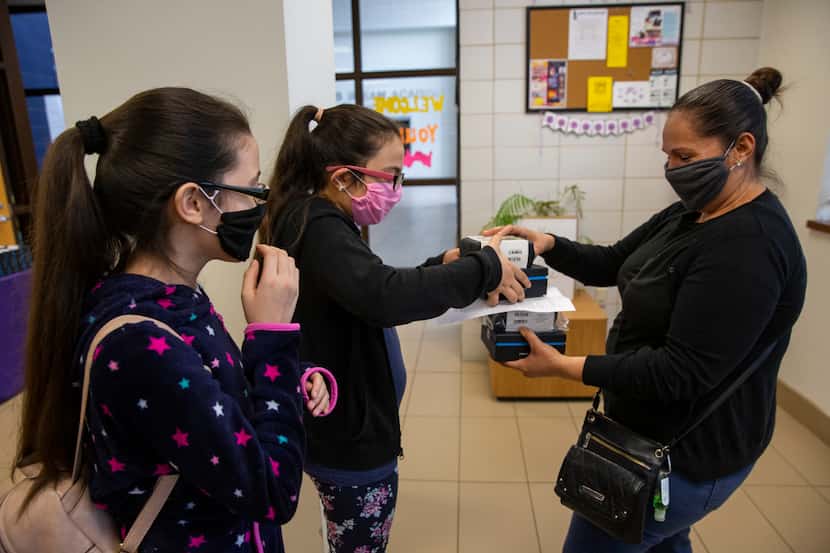 (From left) Adlemi Morales, 13, and Emeline Morales, 11, grab WiFi hotspots provided by DISD...