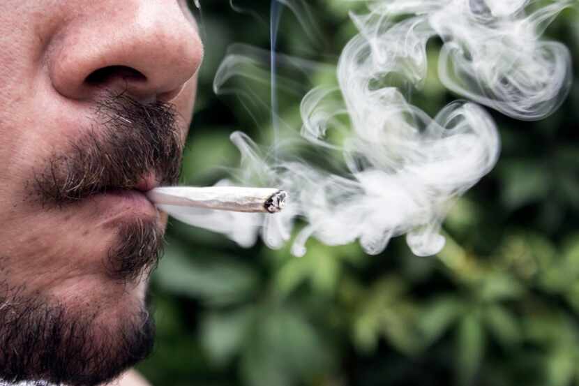 Una persona fuma un cigarrillo de marihuana.