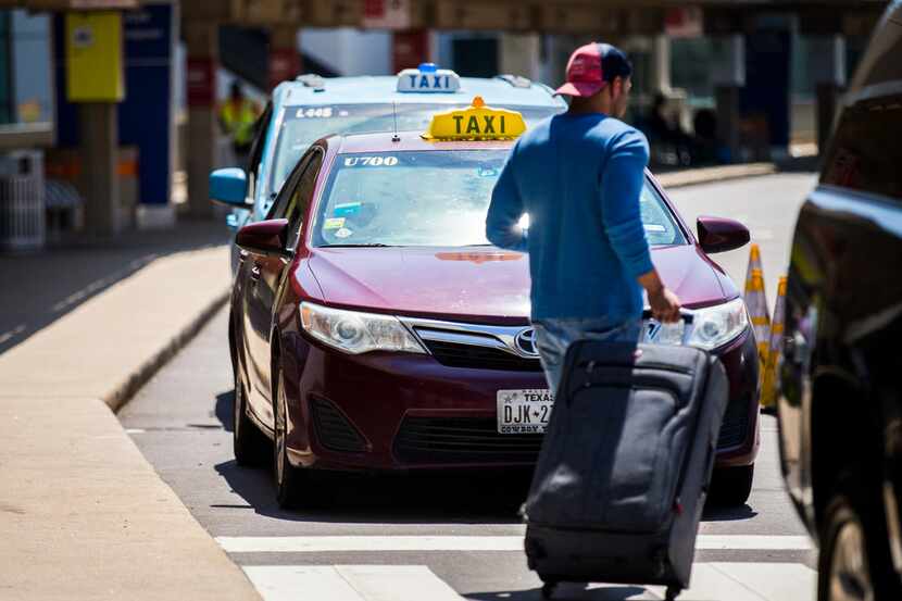 A traveler passes taxi cabs waiting for customers at Terminal A at DFW International Airport.
