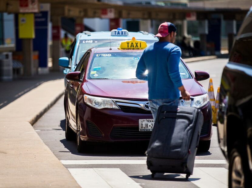 A traveler passes taxi cabs waiting for customers at Terminal A at DFW International Airport.