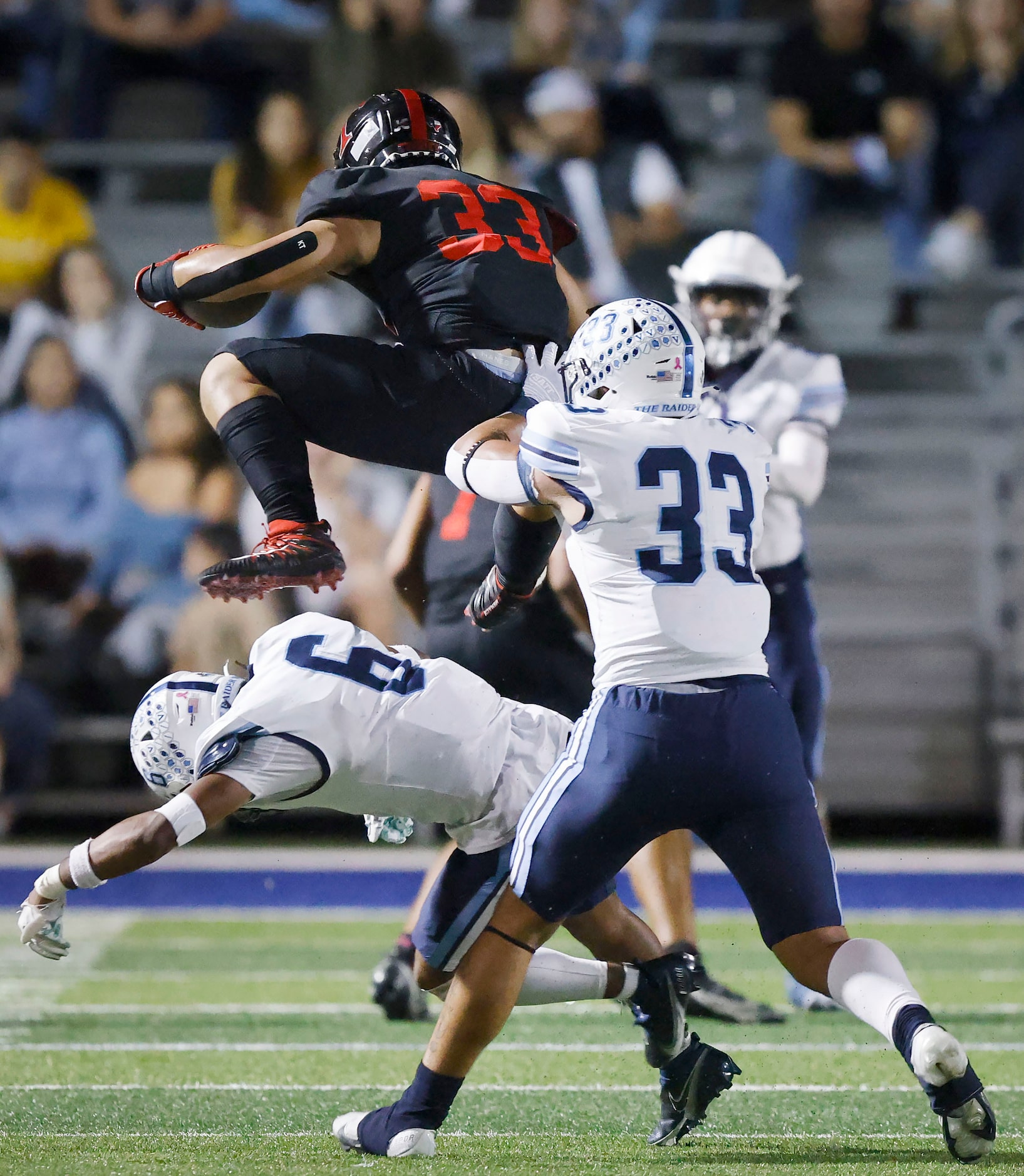 Euless Trinity running back Buddy Leota (33) hurdles Hurst L.D. Bell defensive back Evenn...