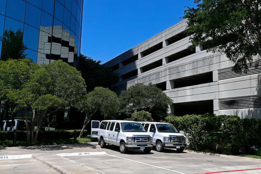 Two white vans are seen near the entrance of an office building where federal agents raided...