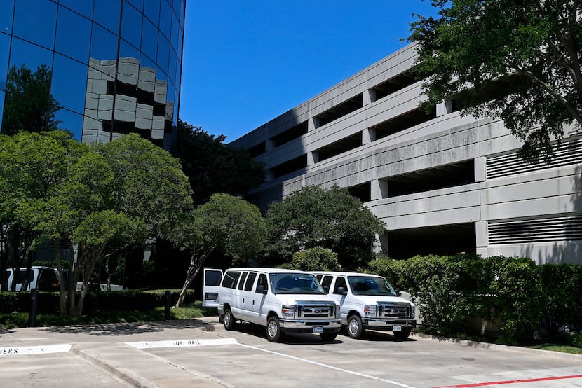 Two white vans are seen near the entrance of an office building where federal agents raided...