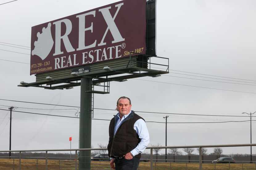 Real estate broker Rex Glendenning stands in front of a company billboard for Rex Real...
