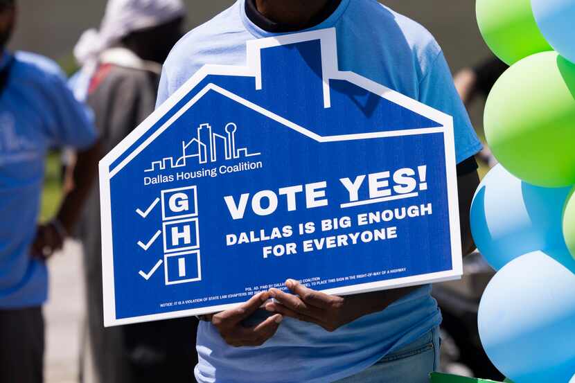 People hold up a “Vote yes!” sign as the Dallas Housing Coalition hosts a rally before they...