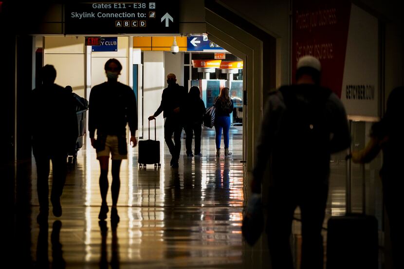 Passengers walk between gates of Terminal E on Saturday, Dec. 11, 2021, at DFW Airport....
